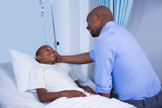 Male doctor consoling patient during visit in ward