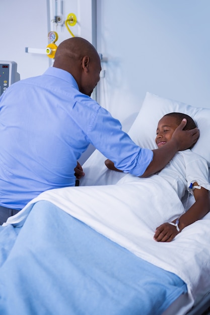 Male doctor consoling patient during visit in ward