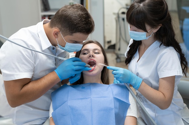 Male doctor dentist and nurse treating teeth of a woman sitting in a chair. Orthodontists are engaged in dental prosthetics. Copy space.