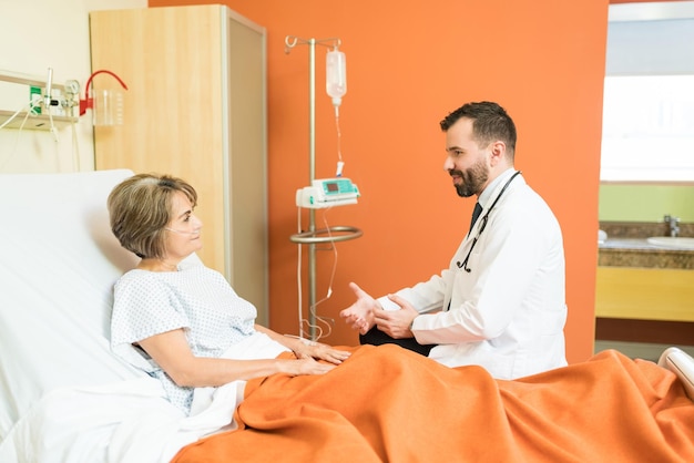 Male doctor discussing over disease to senior patient in hospital