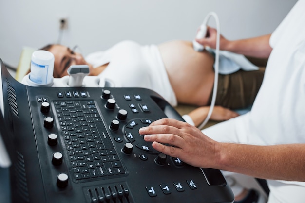 写真 男性医師は病院で妊婦のために超音波検査を行います。