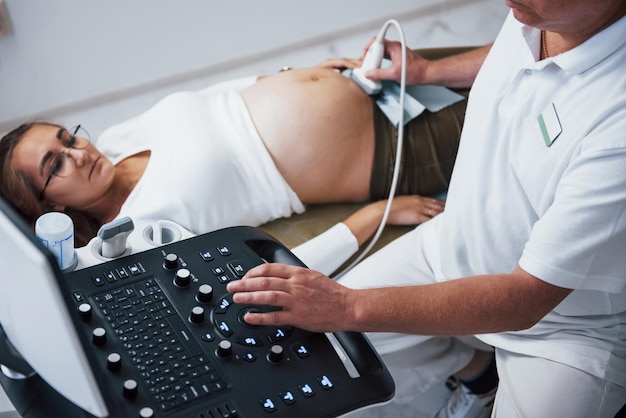 Photo male doctor does ultrasound for a pregnant woman in the hospital