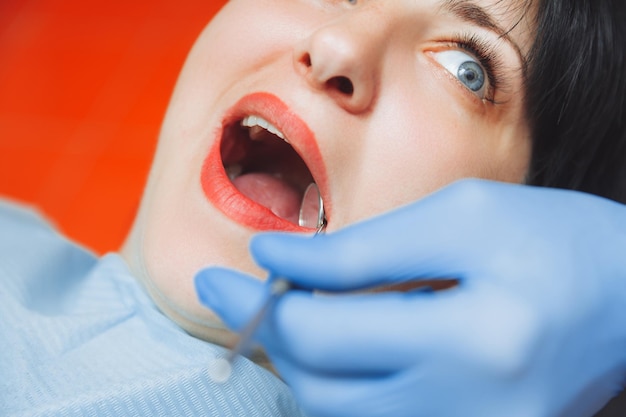 A male doctor examines the oral cavity of a young patient\
sitting in a dentist\'s chair in the office next to the dentist the\
concept of healthy teeth