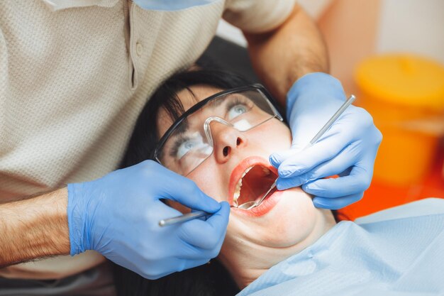 A male doctor examines the oral cavity of a young patient
sitting in a dentist's chair in the office next to the dentist the
concept of healthy teeth