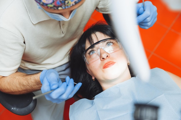 A male doctor examines the oral cavity of a young patient
sitting in a dentist's chair in the office next to the dentist the
concept of healthy teeth