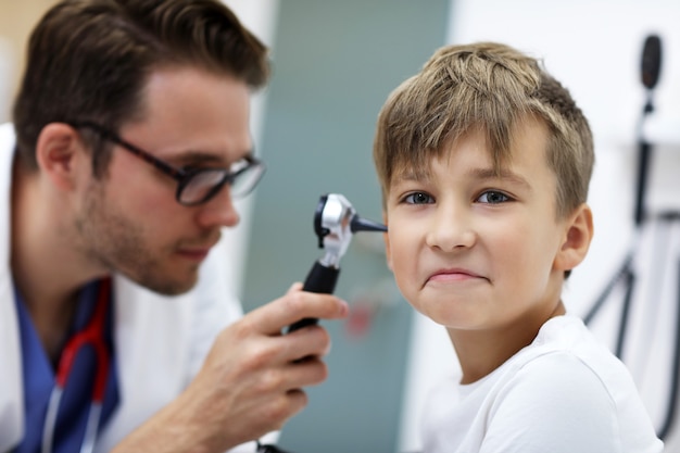 Male Doctor Examining Boy's Ear With An Otoscope