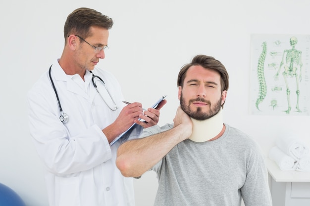 Male doctor examining a patients sprained neck