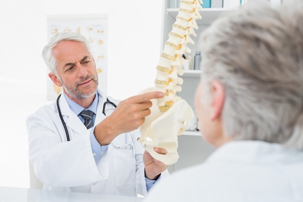 Male doctor explaining the spine to senior patient