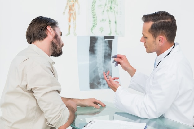 Male doctor explaining spine xray to patient