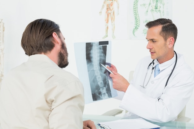 Male doctor explaining spine xray to patient