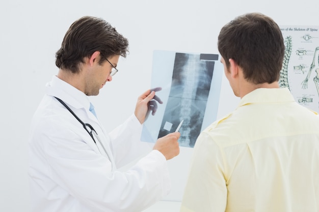 Male doctor explaining spine xray to patient