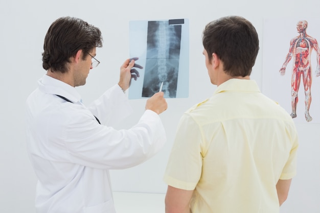 Male doctor explaining spine xray to patient