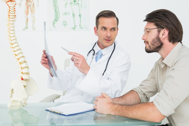 Male doctor explaining spine xray to patient