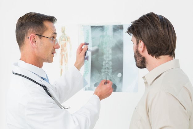 Male doctor explaining spine xray to patient