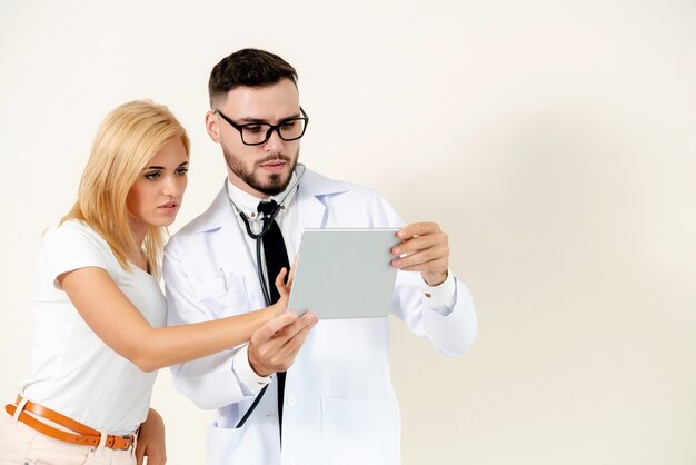 Male doctor and female patient looks at tablet computer for health data record.