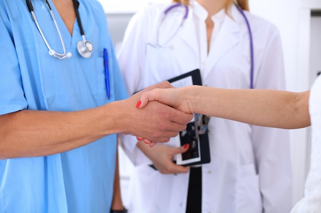 Male doctor and female patient shaking hands. Partnership, trust and medical ethics concept.