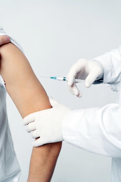 A male doctor gives an injection syringe vaccination into the patient's shoulder