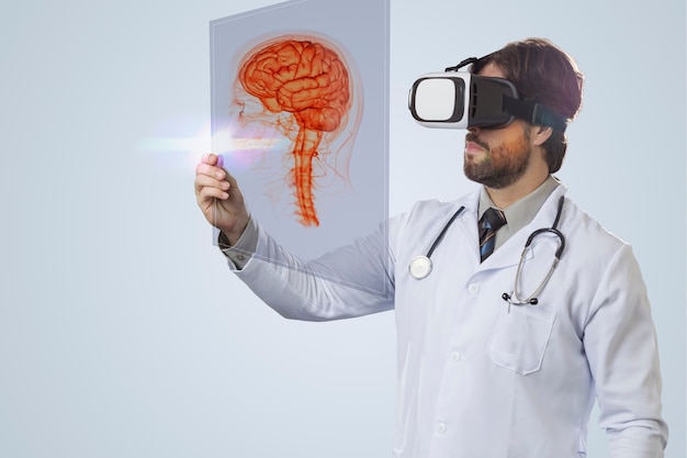Male doctor on a gray wall, using a Virtual Reality Glasses, looking at a virtual brain
