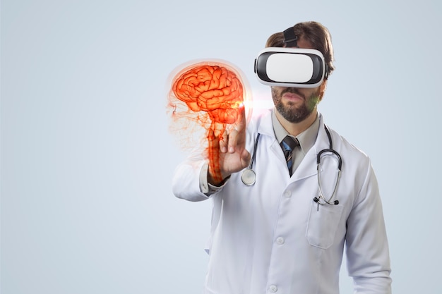 Male doctor on a gray wall, using a Virtual Reality Glasses, looking at a virtual brain