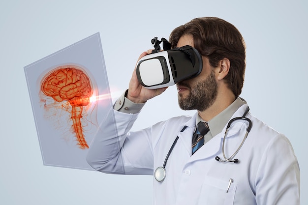 Male doctor on a gray wall, using a Virtual Reality Glasses, looking at a virtual brain