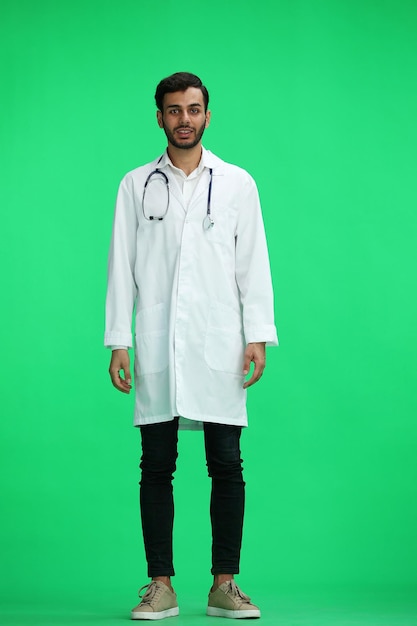 Male doctor on a green background in full growth