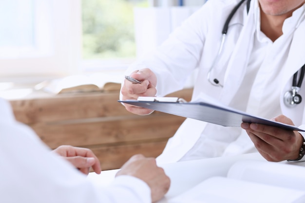Photo male doctor hand hold silver pen and showing pad.