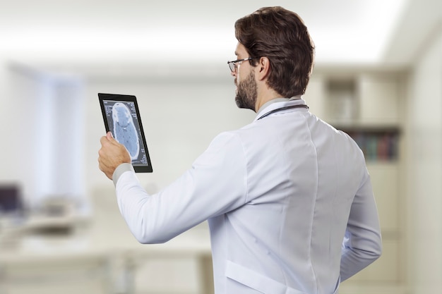 Male doctor in his office, looking at a tablet