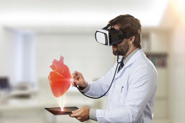 Medico maschio nel suo ufficio, utilizzando occhiali per realtà virtuale, guardando un cuore virtuale