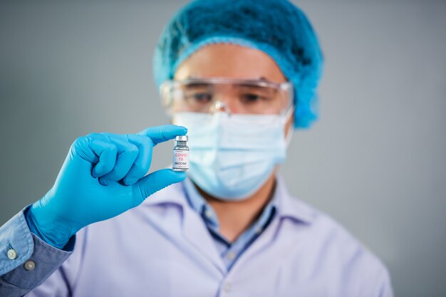 Male doctor holding Coronavirus (Covid-19) vaccine bottle for injection medicine