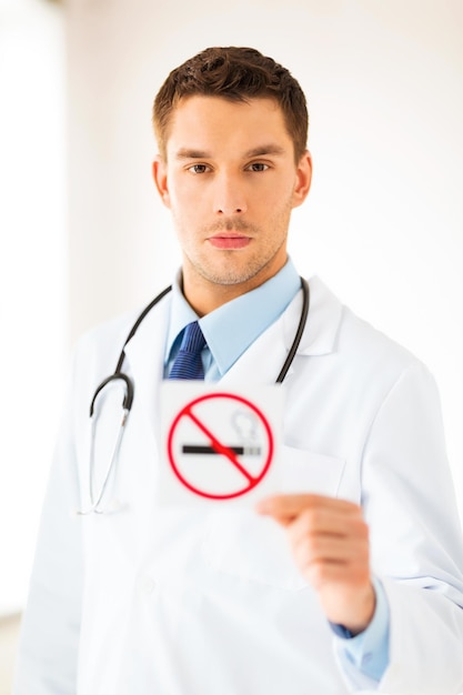 Medico maschio con in mano un cartello per non fumatori