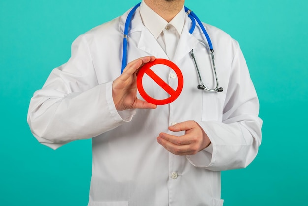 青色の背景に禁止標識を保持している男性医師
