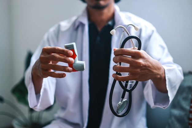Photo male doctor holding and showing stethoscope and inhaler in hand healthcare and medicine concept