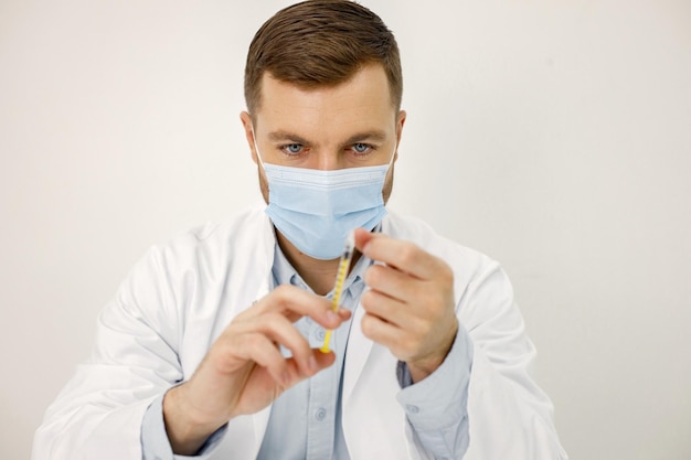 Male doctor holding a syringe while sitting isolated on white background