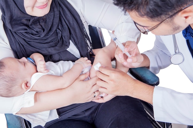 Male doctor injecting vaccine to a baby in hospital