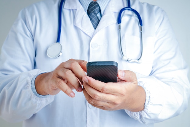 The male doctor is pressing the mobile phone to contact.