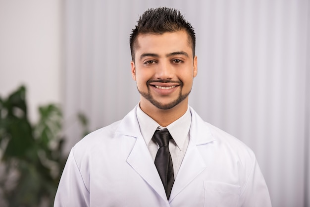 A male doctor is standing in a clinic and smiling.