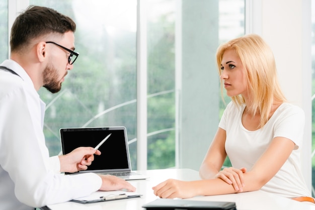 Male doctor is talking to female patient in hospital office. Healthcare and medical service.