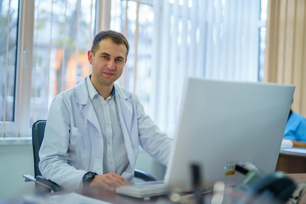 Male doctor is working in hospital office at computer Medic in scrubs at clinic