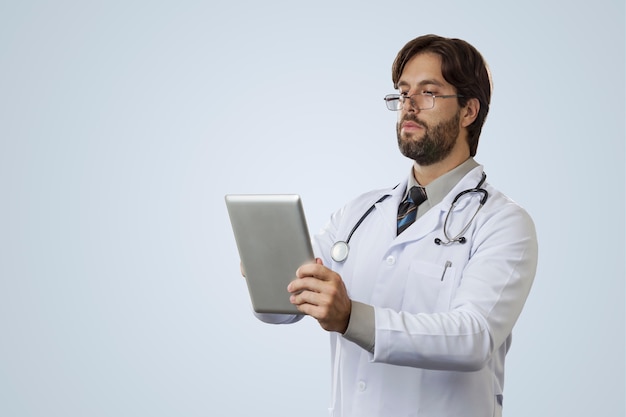 Male doctor  , looking at a tablet.