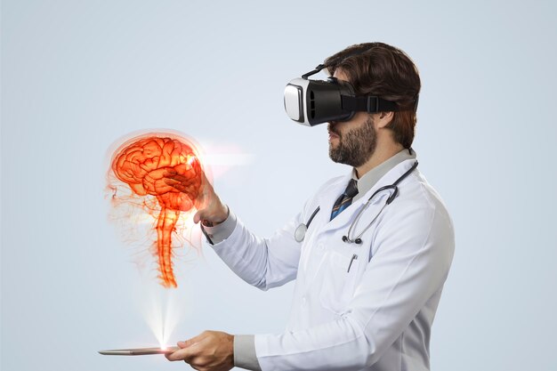 Male doctor looking at a virtual brain coming out of a tablet on a gray wall