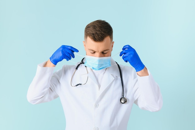 Male doctor in medical mask on color background