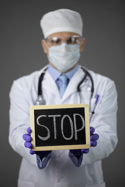 Photo male doctor in medical uniform, protective mask and glasses holding stop sign