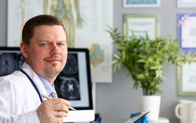 Male doctor in office looking in camera