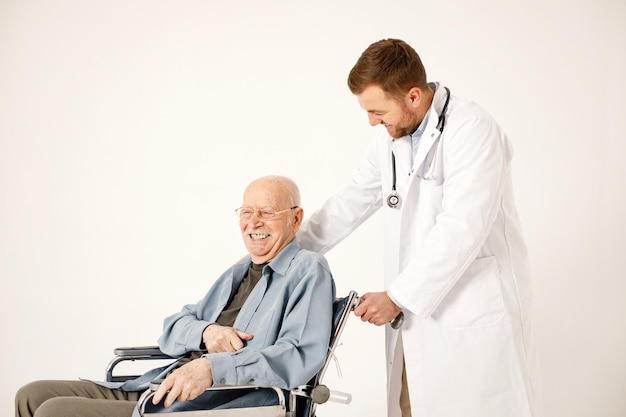 흰색 배경에 고립 된 휠체어에 남자 의사와 노인