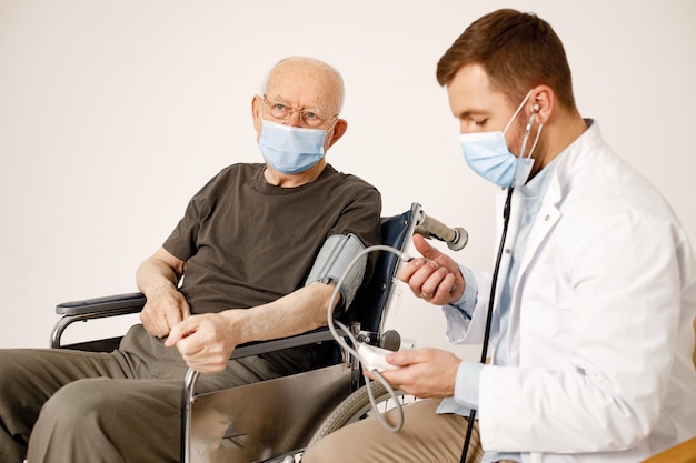 Male doctor and old man on a wheelchair isolated on a white background