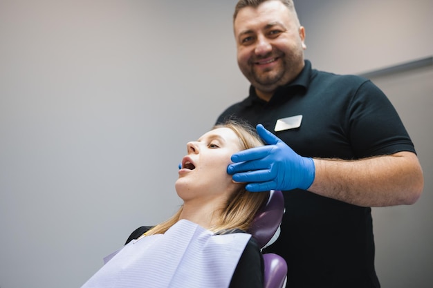 Male doctor orthodontistgnathologist palpates the jaw joints of the female patient