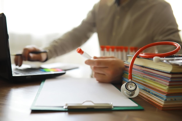 Male doctor search information in book and writtnig prescription medical stethoscope on the desk at clinic Medical knowledge and education concept