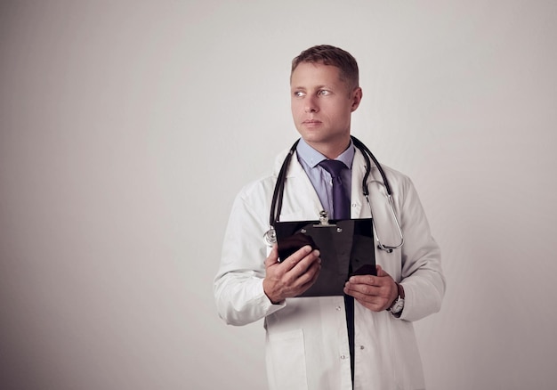 Мужчина-врач, стоящий с папкой на белом фоне
