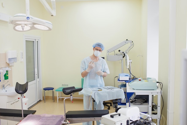 A male doctor taking a surgical instrument for a group of\
surgeons in the background in the surgery room steel medical\
instruments ready to use the concept of surgery and emergency\
care