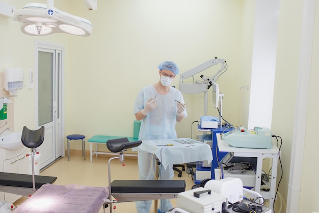 A male doctor taking a surgical instrument for a group of\
surgeons in the background in the surgery room steel medical\
instruments ready to use the concept of surgery and emergency\
care